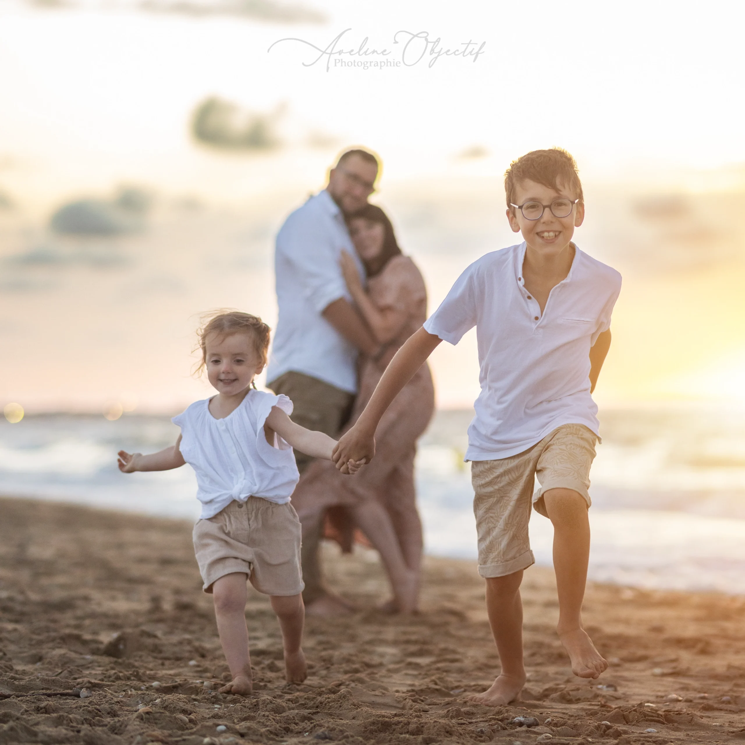 Photo famille plage enfants courant main dans la main coucher de soleil Normandie