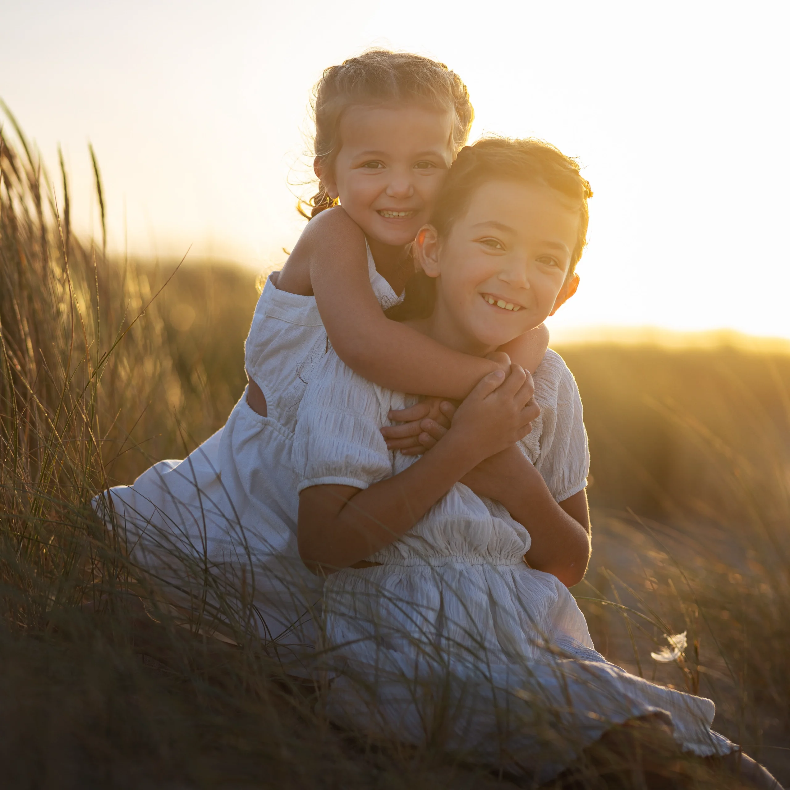 Portrait frère et sœur câlin dunes herbes folles golden hour shooting famille