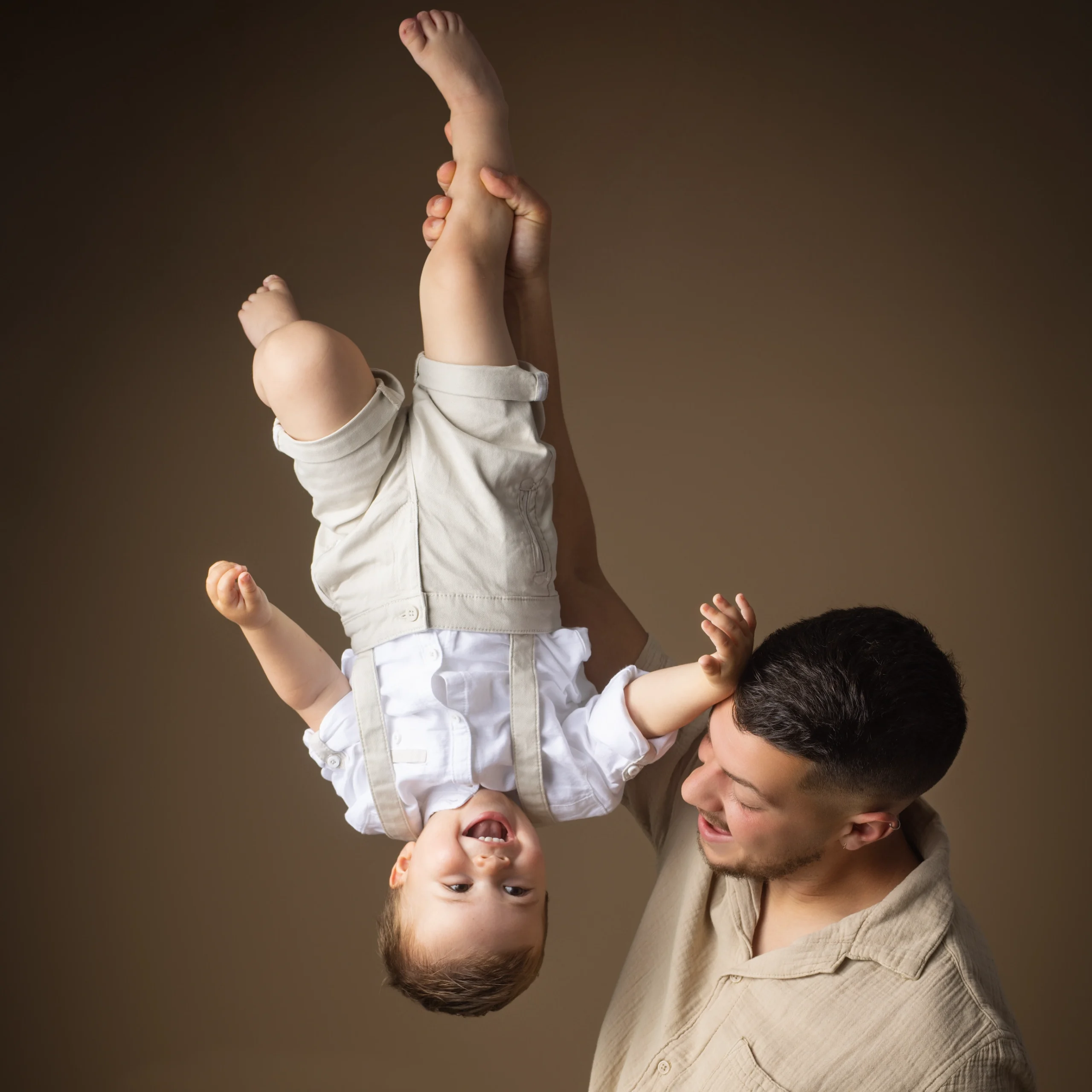 Shooting studio père et bébé jeu renversé fond marron photographe famille Caen